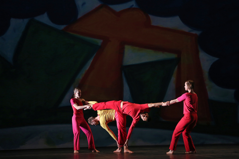 Two women stretch two men by holding their wrists and foot